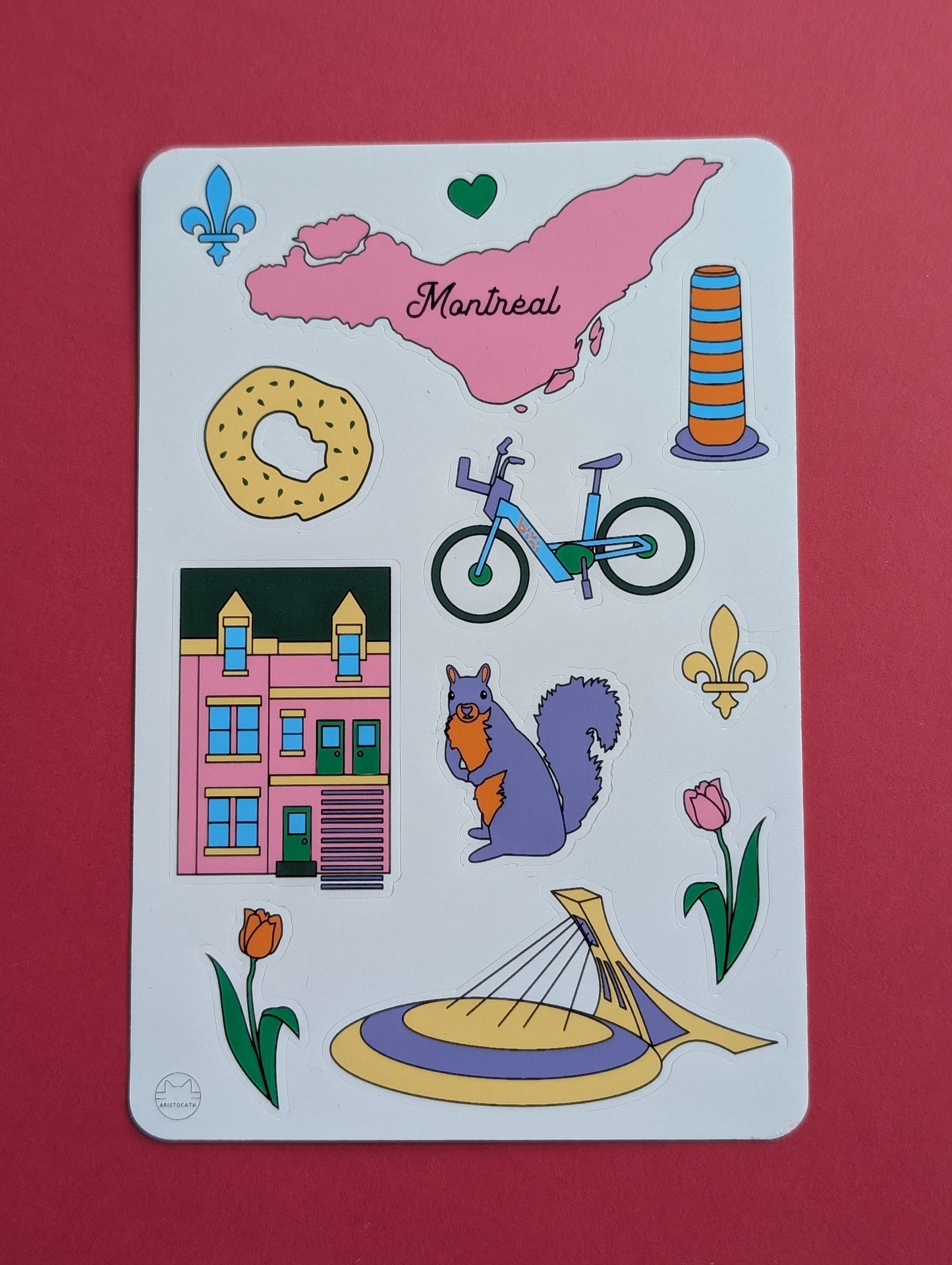 Sticker sheet with various illustrations including a map of Montreal, a bagel, a bixi bicycle, a building, a squirrel, and flowers on a red background.