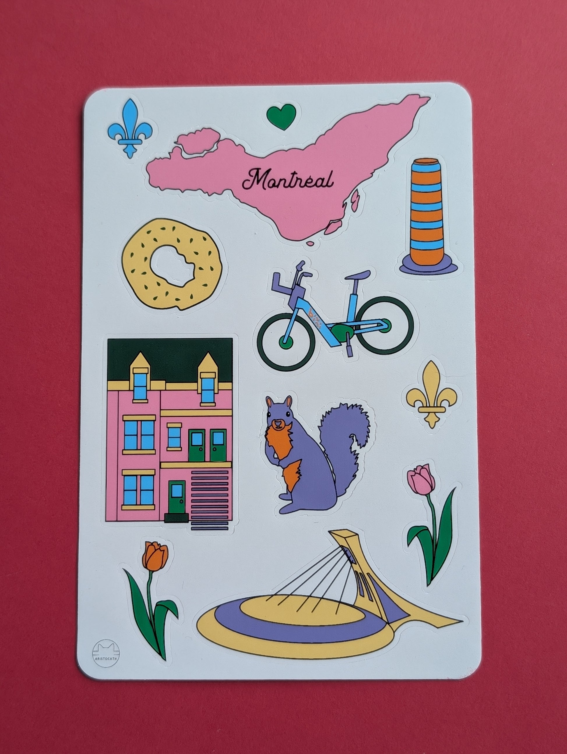 Sticker sheet with various illustrations including a map of Montreal, a bagel, a bixi bicycle, a building, a squirrel, and flowers on a red background.