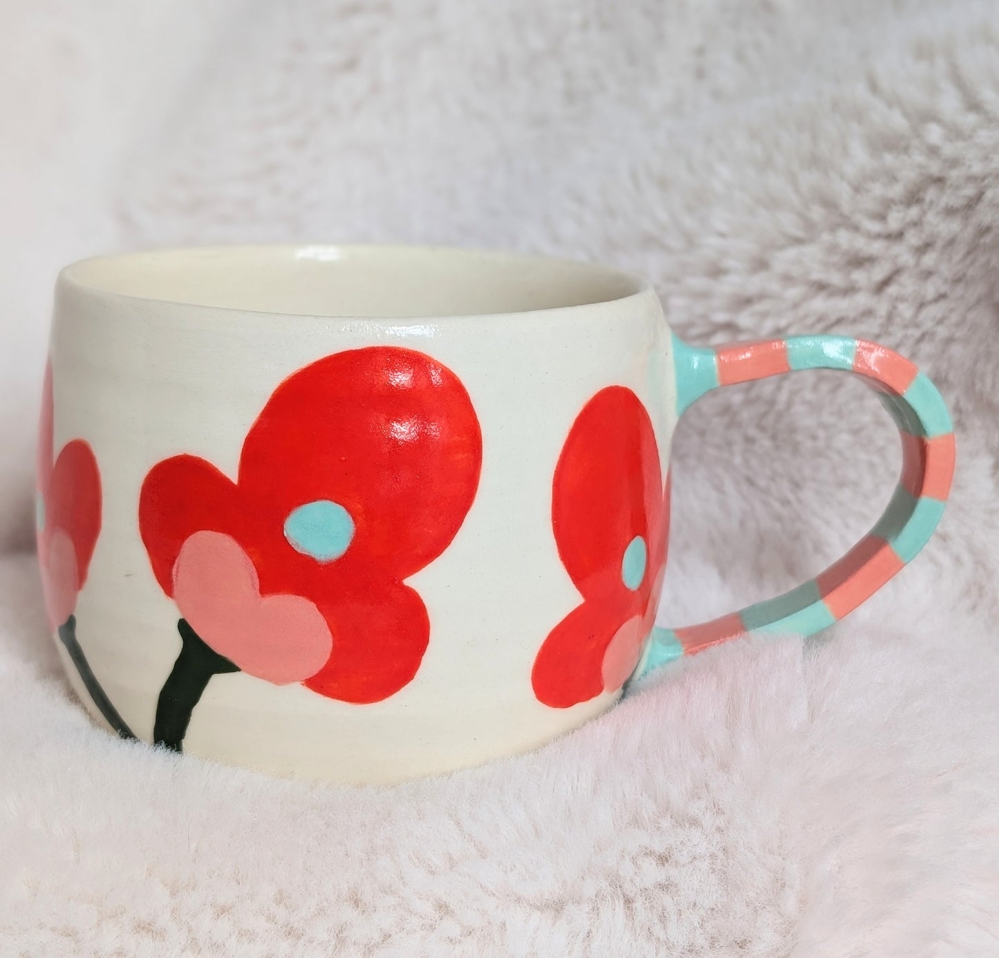 White mug with red coral floral design and colorful handle on a white background